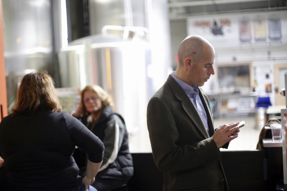 Brit Vitalius, spokesman for Say No to Rent Control, checks his phone while attending an election results gathering Tuesday at Rising Tide Brewing Co. in Portland.