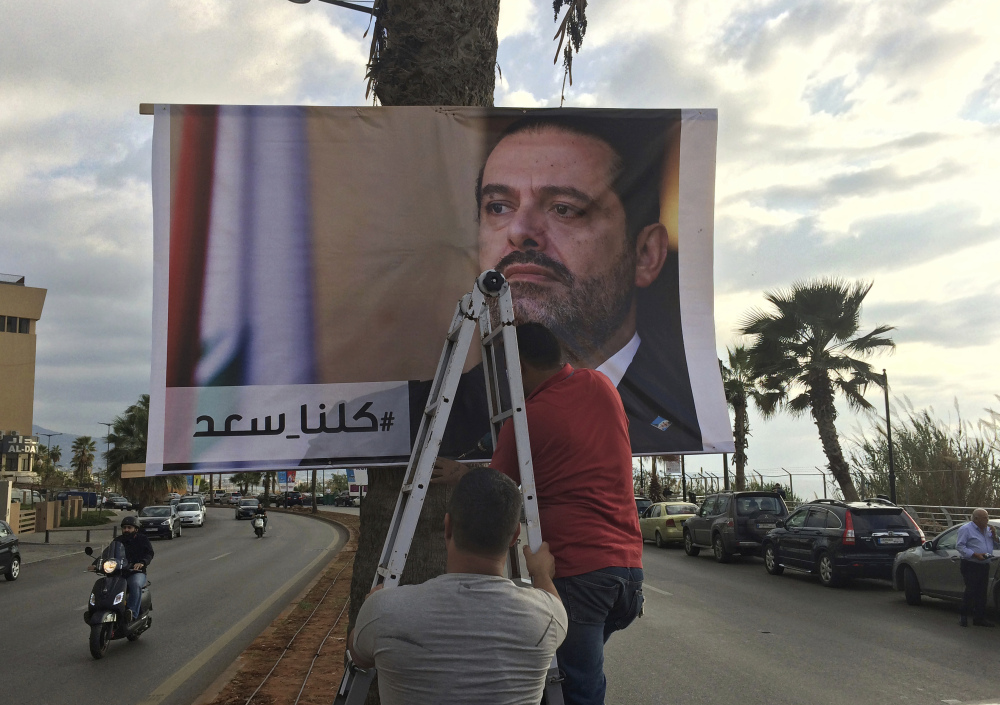 Workers hang a poster of outgoing Prime Minister Saad Hariri with Arabic words that read, "We are all Saad," on a seaside street in Beirut, Lebanon, Thursday, Nov. 9, 2017. Hezbollah has called on Saudi Arabia to stay out of Lebanese affairs, saying the resignation of Prime Minister Saad Hariri, announced from Riyadh over the weekend, "has raised many questions." (AP Photo