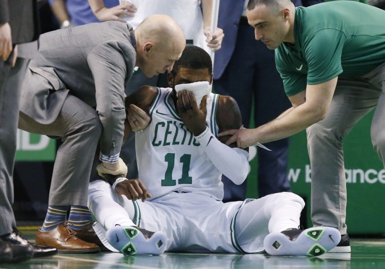 Team personnel assist Boston's Kyrie Irving after he was injured in the first quarter Friday night against the Charlotte Hornets in Boston. Irving took an elbow to the face and left the game.