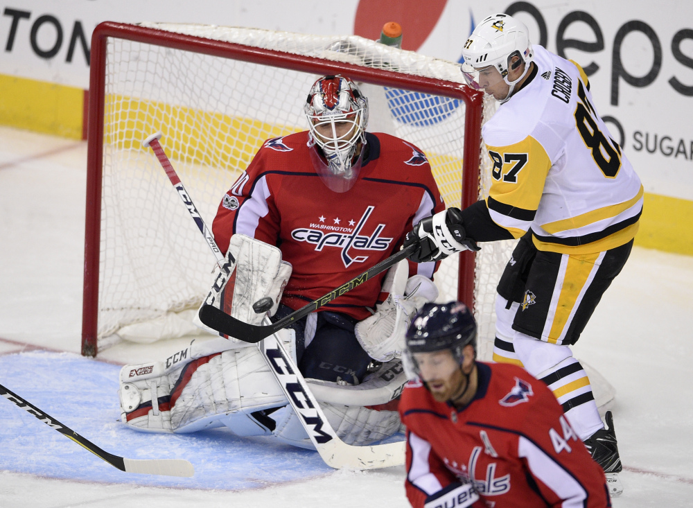 Penguins center Sidney Crosby battles for the puck against Washington goalie Braden Holtby in the third period Friday night in Washington. Holtby became the second-fastest goaltender in NHL history behind Ken Dryden to reach 200 victories with a 4-1 win.