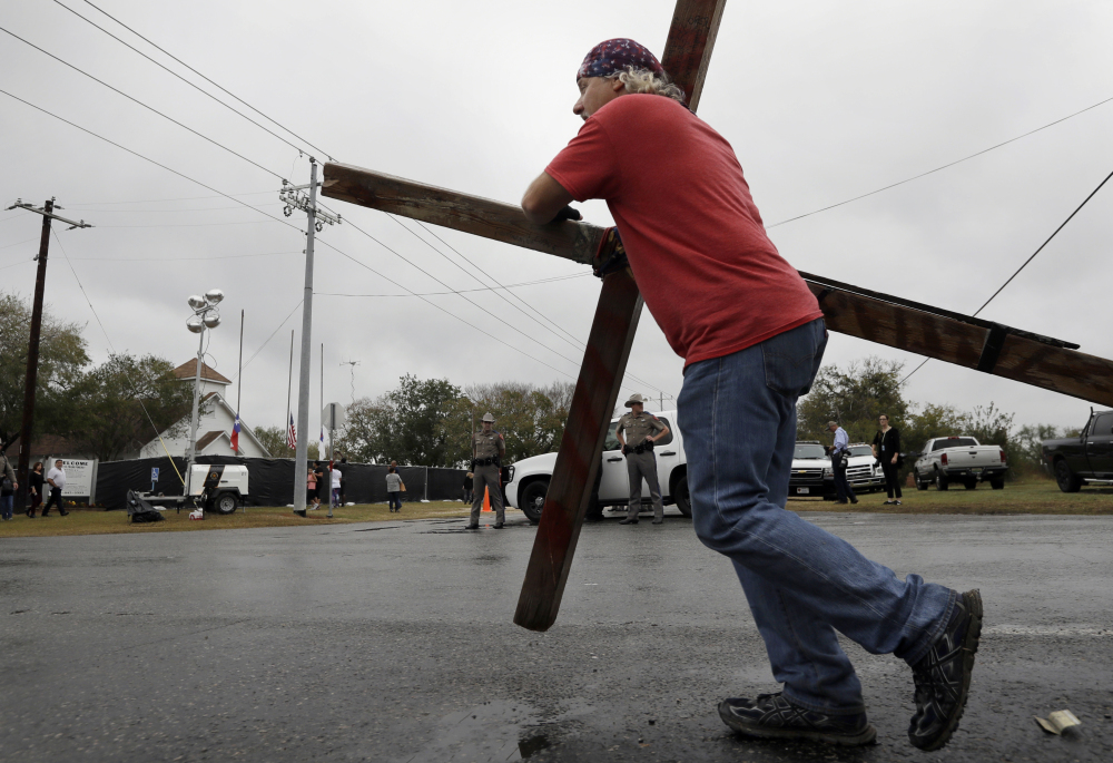 Stephen Hope carries a cross past the Sutherland Springs First Baptist Church in Texas after services held at a temporary site on Sunday, a week after 26 people were killed in the church.