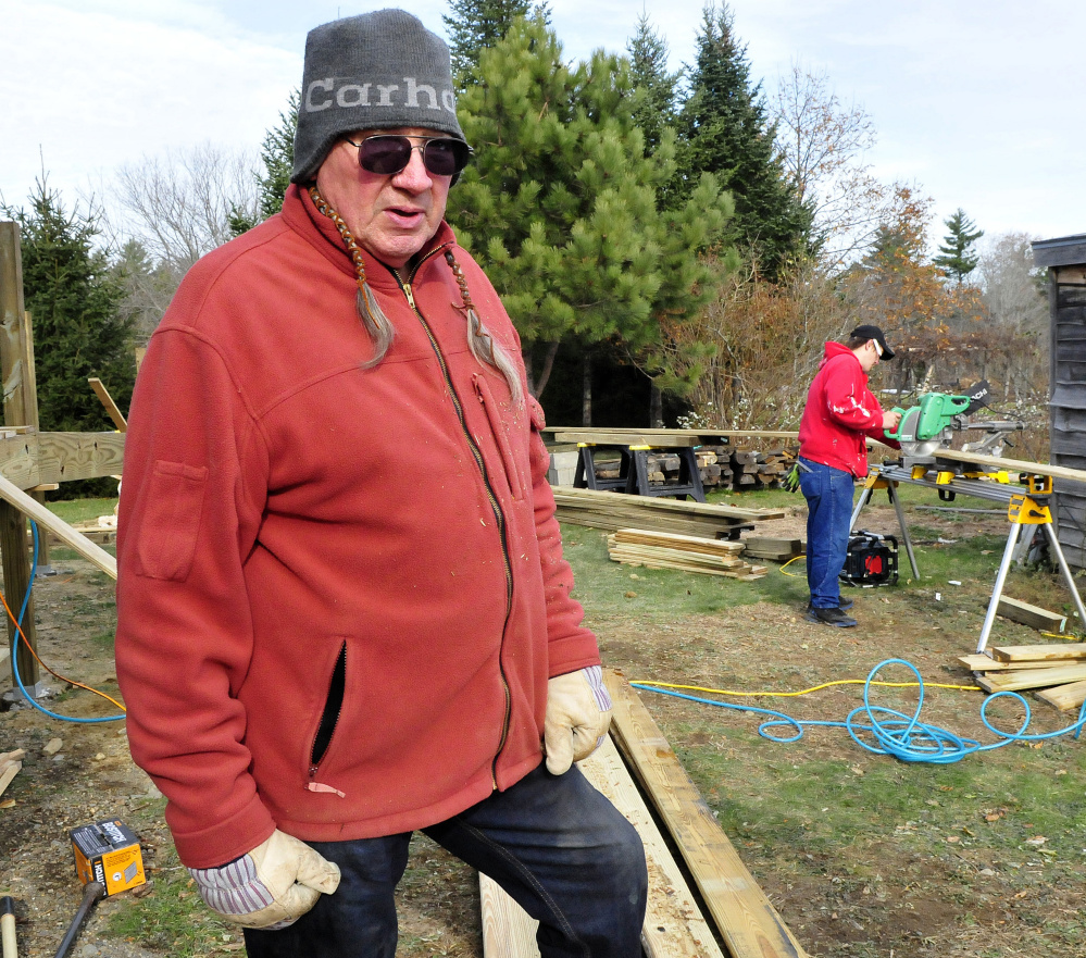 Phil White Hawk talks about the new wheelchair ramp under construction at the Palermo Community Center on Sunday. At right, Brian Taylor cuts wood for the project.