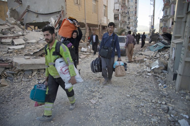 People carry their belongings in Sarpol-e-Zahab, western Iran after a powerful 7.3 magnitude earthquake struck the Iraq-Iran border region on Monday and killed more than 300 people in both countries.