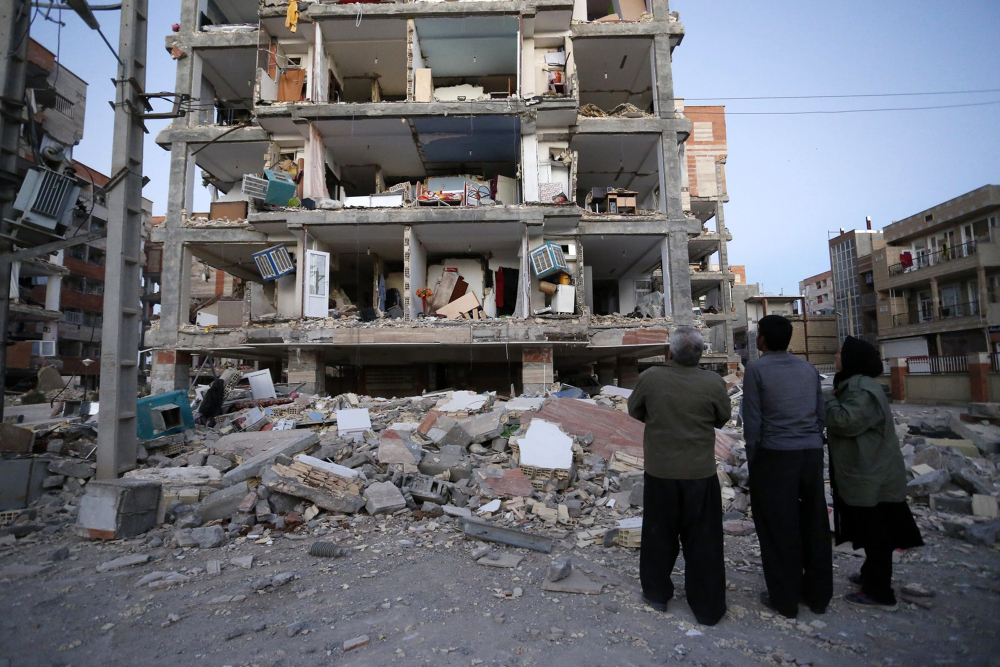 People look at destroyed buildings after an earthquake at the city of Sarpol-e-Zahab in western Iran.