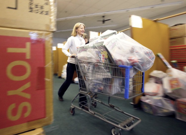 Barbi Diaz of Cape Elizabeth, a volunteer for the Portland Press Herald Toy Fund, pushes a cart full of toys that are destined for children this Christmas. Volunteers have been working since August to organize more than 10,000 toys for donations to families.
