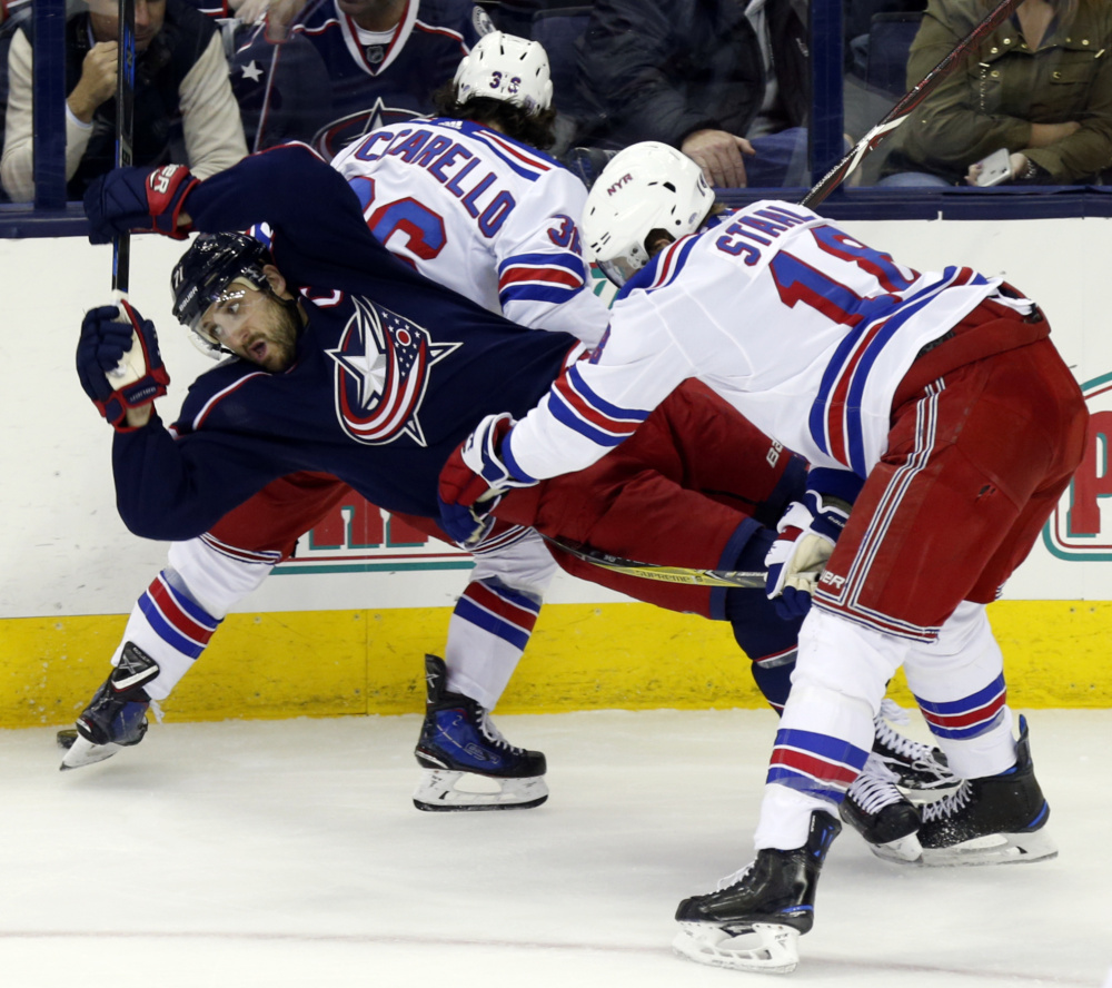Rangers defenseman Marc Staal, right, checks Columbus' Nick Foligno, left, behind Rangers forward Mats Zuccarello in the third period Friday night in Columbus, Ohio.