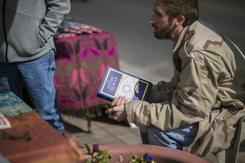 Zack Kershaw, a visitor to the Islamic Center's table, holds a Koran.