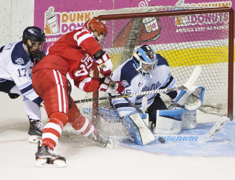 Maine goalie Rob McGovern gets a stick in front of a shot by Brady Tkachuk of Boston University as Maine defenseman Dante Fabro closes in Saturday night during BU's 7-0 victory at Cross Insurance Arena.