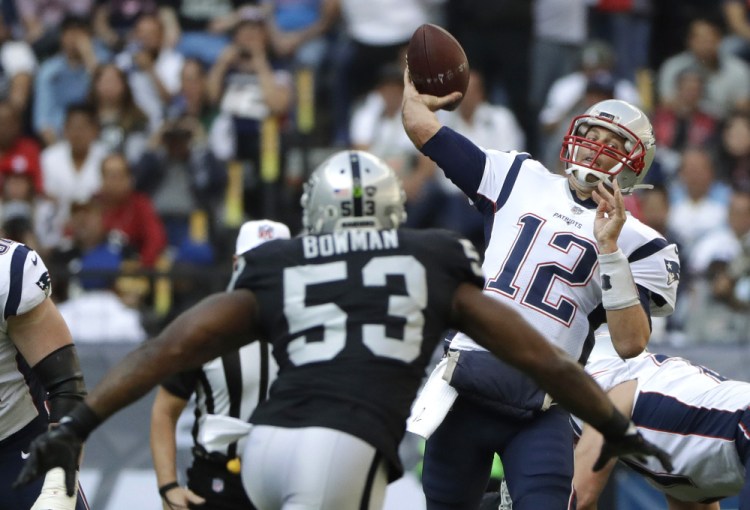 Patriots quarterback Tom Brady releases a pass under pressure from Raiders linebacker NaVorro Bowman. Brady went over the 300-yard mark for the sixth time this season, leading New England to a 33-8 win in Mexico City.