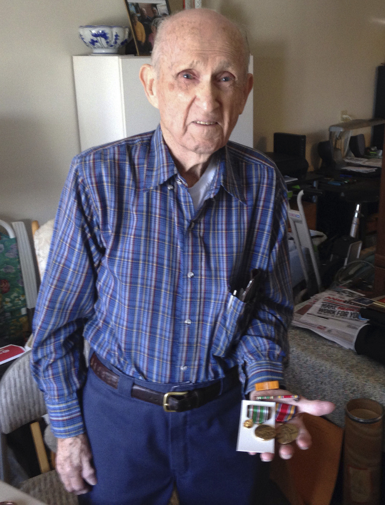 In this Tuesday, Nov. 21, 2017, photo, World War II veteran Kenneth F. Lincoln, 90, displays at his North Attleborough, Mass., home some of the medals he earned while serving in the U.S. Navy. Lincoln is finally getting the military decoration he earned for fighting a large fire that broke out among straw huts in Rabat, Morocco in the summer of 1946. He will receive a Moroccan award for meritorious conduct on Sunday, Nov. 26 in North Attleborough. (AP Photo/ Jennifer McDermott)