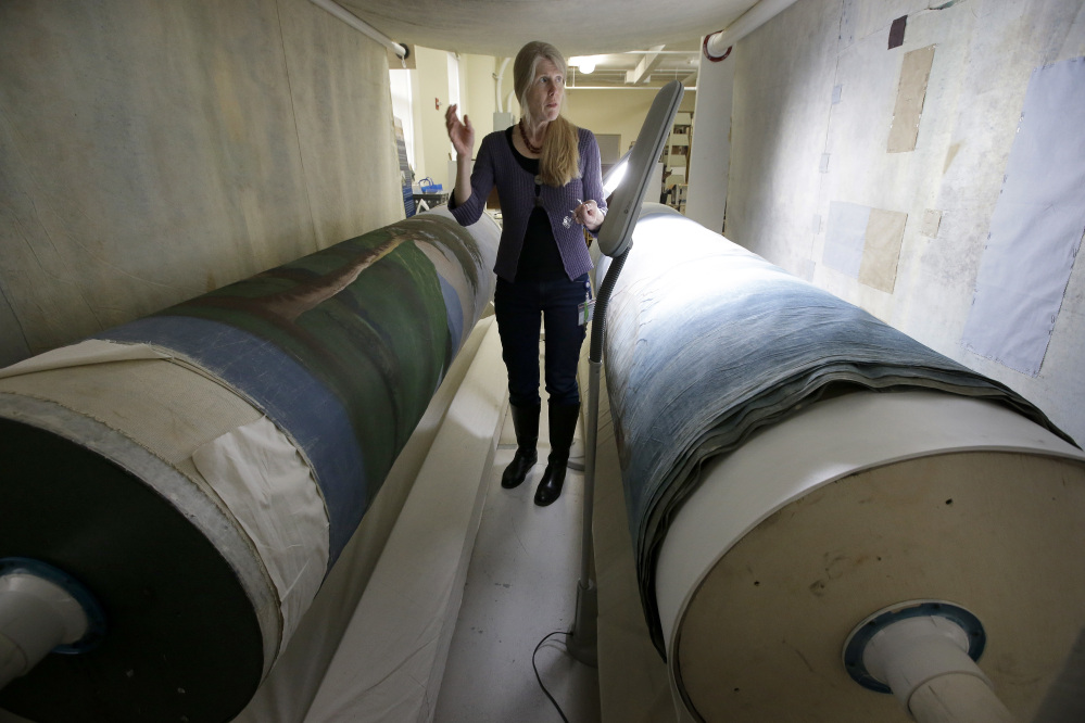 Textile conservator Kate Tarleton of Rochester, Mass., stands between two oversized spools holding part of the "Grand Panorama of a Whaling Voyage Round the World," at the New Bedford Whaling Museum in Massachusetts.