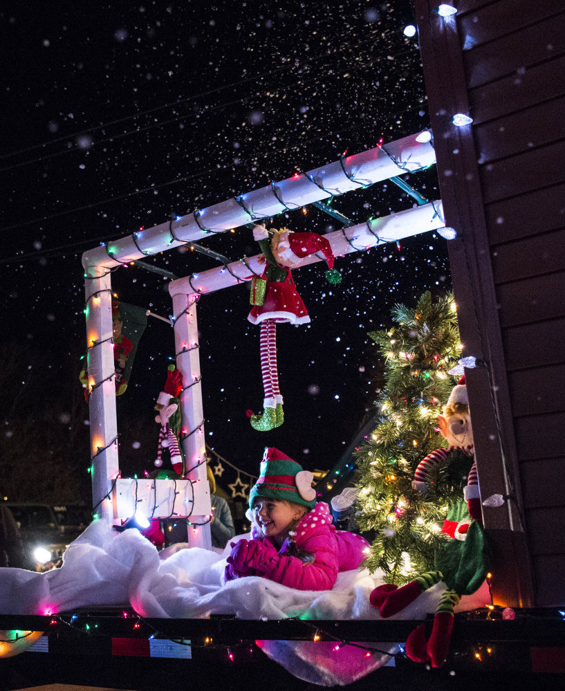 Hannah Hillman, 4, sits in on the Little Friends Daycare float as "snow" falls Friday. Above right, 7-year-old Lyrian Thomas, dressed as a sheep, lets her nose shine.