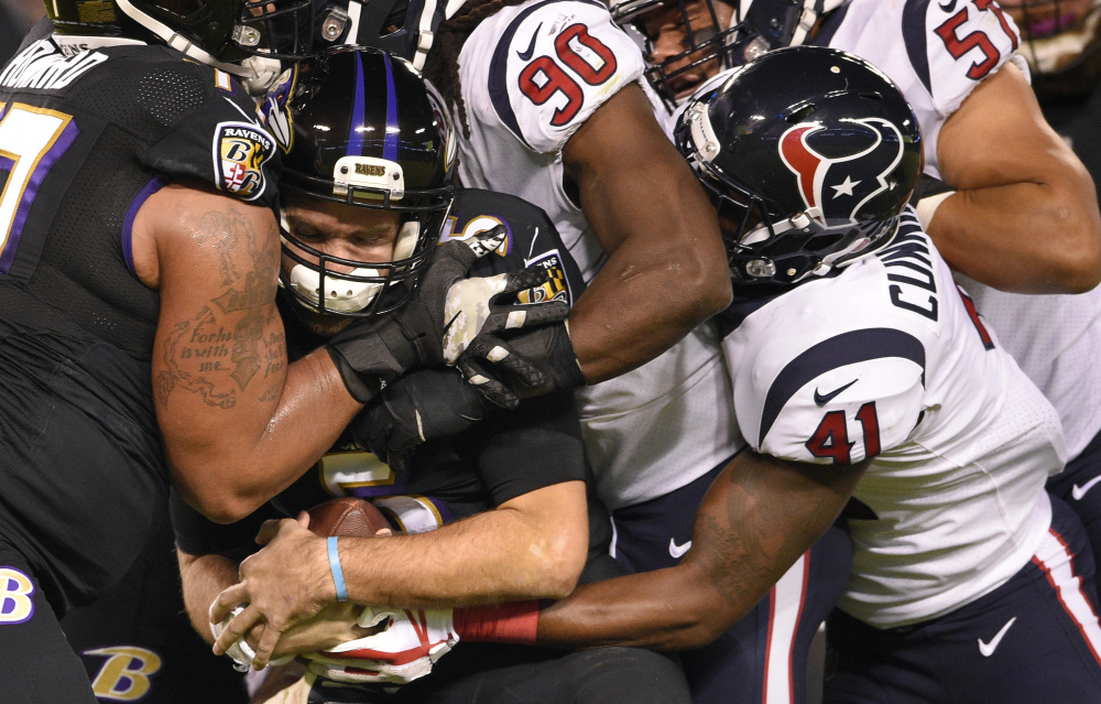 Ravens quarterback Joe Flacco, second from left, is sacked by Houston outside linebacker Jadeveon Clowney, 90, in the first half of their game Monday in Baltimore. The Ravens beat the Texans, 23-16.