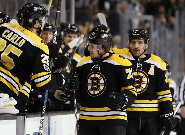 Boston's Charlie McAvoy is congratulated by Patrice Bergeron and Brandon Carlo, 25, after scoring in the first period Wednesday night in Boston against the Tampa Bay Lightning.
