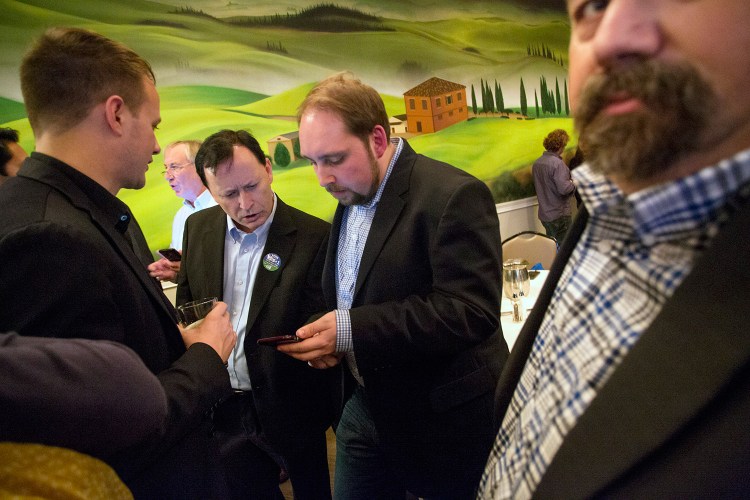 Shawn Scott, second from left, looks at a phone with campaign press secretary Michael Sherry while awaiting election results at Bruno's restaurant in Portland on Tuesday. Scott's company would have been the only one allowed to hold the license for a proposed York County casino, which failed at the ballot box.