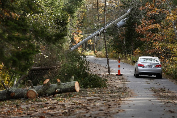 A motorist drives under a falled utility pole propped up by a pine tree limb on High Head Road in Harpswell on Wednesday.