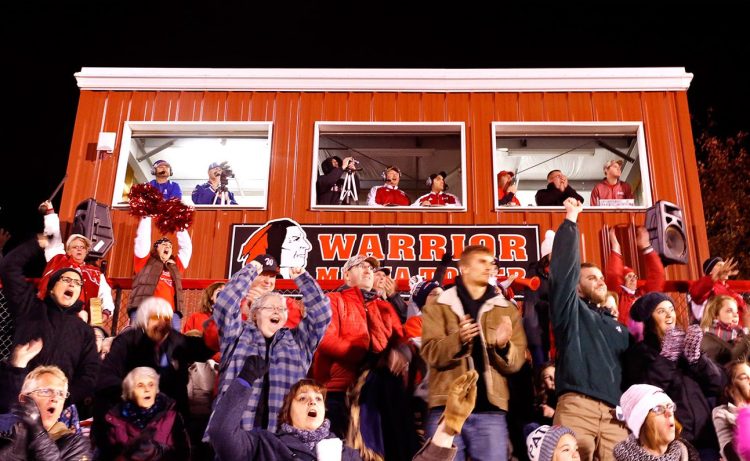 A Native American-themed logo adorns the Wells High School press box behind a crowd of cheering fans during last Friday's game between the Wells Warriors and Oak Hill.