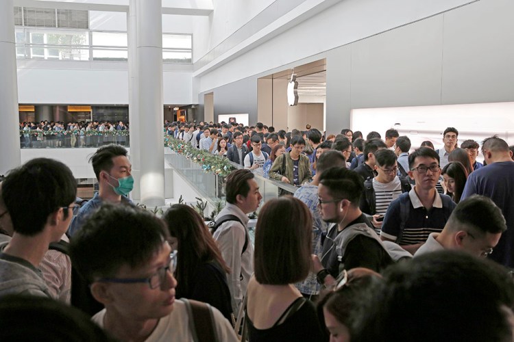 Customers line up to buy the new iPhones they previously reserved online at an Apple Store in Hong Kong, Friday.