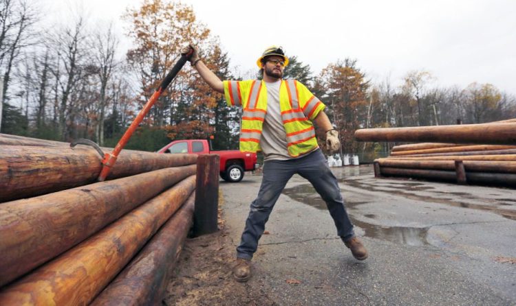 Central Maine Power Co. worker Jason Valera loosens a utility pole from a pile before it's lifted onto a trailer in Brunswick on Monday.