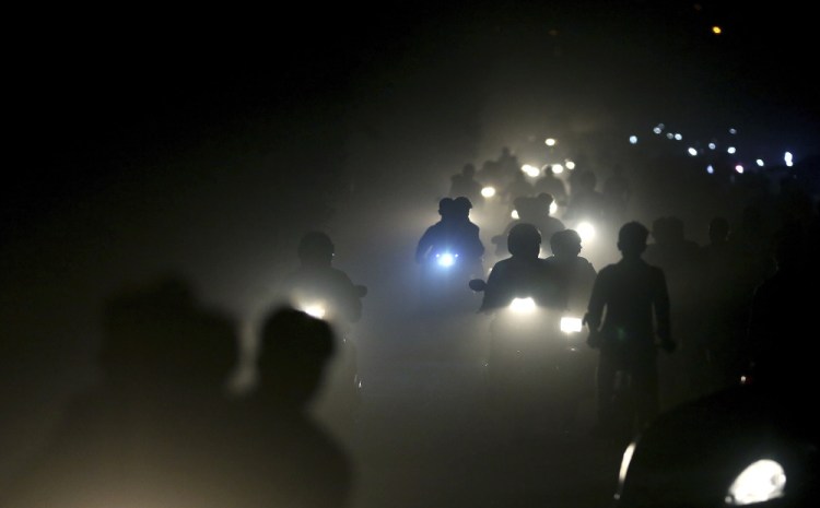 Indian commuters ride past a thick blanket of smog and dust on the outskirts of New Delhi, in a photo from Nov. 10. The petroleum coke  being burned in countless factories and plants is contributing to dangerously filthy air in the Asian country, which already has many of the world's most polluted cities. India's energy-hungry industries like petcoke because it's cheaper and burns hotter than coal.