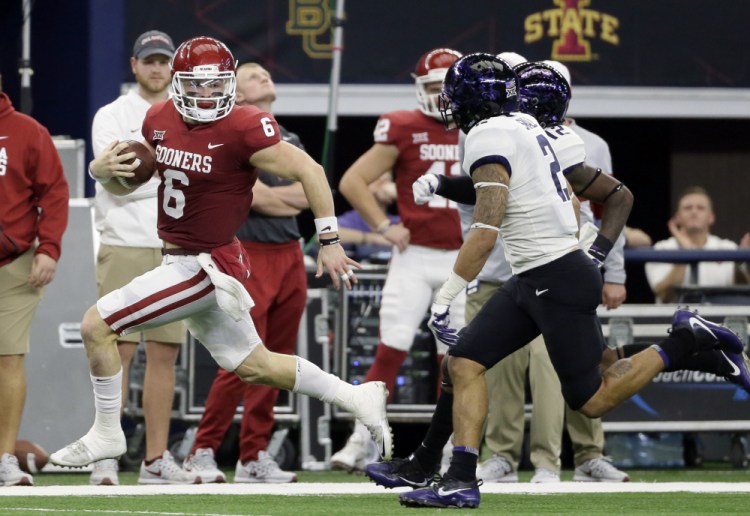 Oklahoma quarterback Baker Mayfield, left, runs for yardage as TCU safety Niko Small gives chase in the first half of the Big 12 Conference championship on Saturday, in Arlington, Texas. The Sooners won, 41-17.