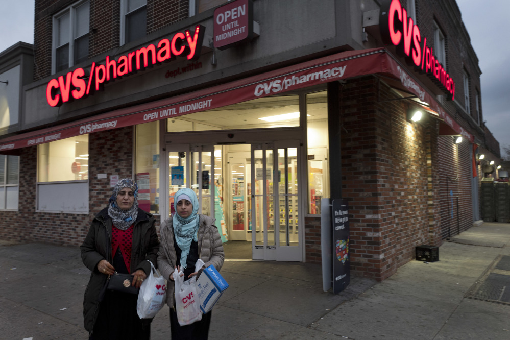 Customers leave a CVS Pharmacy, Sunday, Dec. 3, 2017 in the Brooklyn borough of New York. CVS will buy insurance giant Aetna in a roughly $69 billion deal that will help the drugstore chain reach deeper into customer health care and protect a key client, a person with knowledge of the matter said Sunday. (AP Photo/Mark Lennihan)