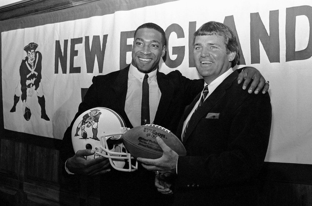 FILE - In this April 11, 1984, file photo, newly signed New England Patriots football player Irving Fryar, left, poses with Patriots coach Ron Meyer during a press conference in Foxborough, Mass. From SMU's "Pony Express" to the NFL's infamous "Snowplow Game," former college and professional football coach Ron Meyer was in the middle of some of the game's most controversial and colorful teams and moments in the 1980s. Meyer died Tuesday, Dec. 5, 2017, in Austin, Texas, at age 76.  (AP Photo/Ted Gartland, File)