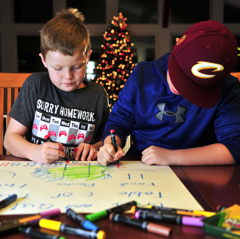 Quincy Emmons, left, and Brady Alexander work on a poster Thursday in Richmond. They plan to staff a table Friday evening at the Richmond tree-lighting to collect nonperishables for the Richmond Food Bank.
