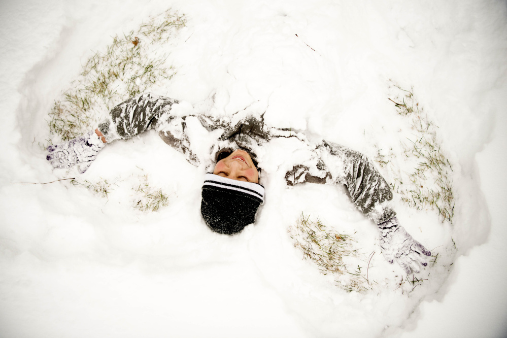 Matt Murphy, 13, makes snow angels in the fresh snow at Veteran's Memorial Park in Waterville after getting out of school early Tuesday.
