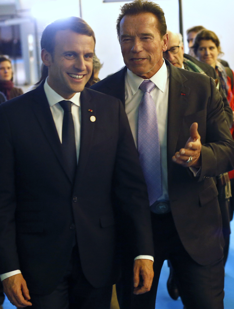 France's President Emmanuel Macron, left, and Arnold Schwarzenegger leave the One Planet Summit near Paris, Tuesday. American leaders there said the world will go greener with or without President Trump.