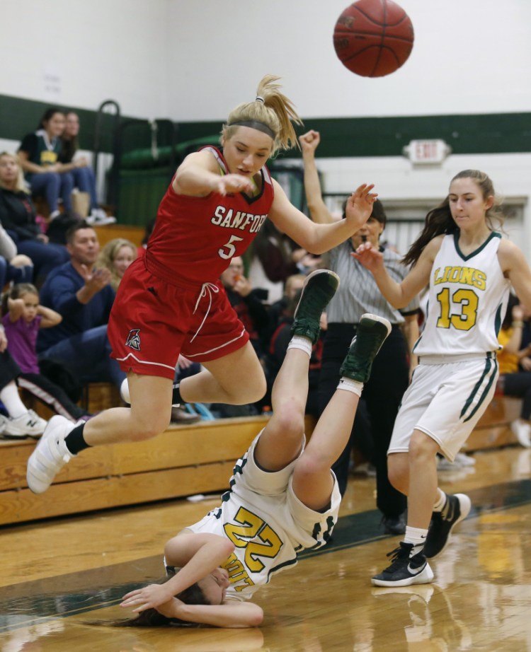 Julia Allen of Sanford leaps over Catherine Reid of Maine Girls' Academy following a midcourt collision Friday night during the third quarter of a 48-41 victory for Maine Girls' Academy. Reid finished with 18 points.