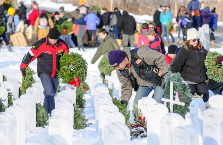 Above, volunteers place wreaths on grave markers Saturday at the Maine Veterans Memorial Cemetery on Mount Vernon Road in Augusta.