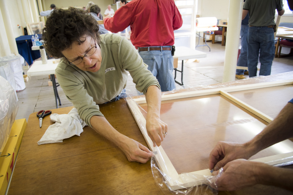 Holly Weidner of Vassalboro cuts excess plastic from a wooden frame as she helps prepare window inserts for residents who needed to insulate their windows. The Friends Advocating for Vassalboro's Older Residents committee gathered community volunteers together over the weekend to measure, build and distribute the plastic windows.