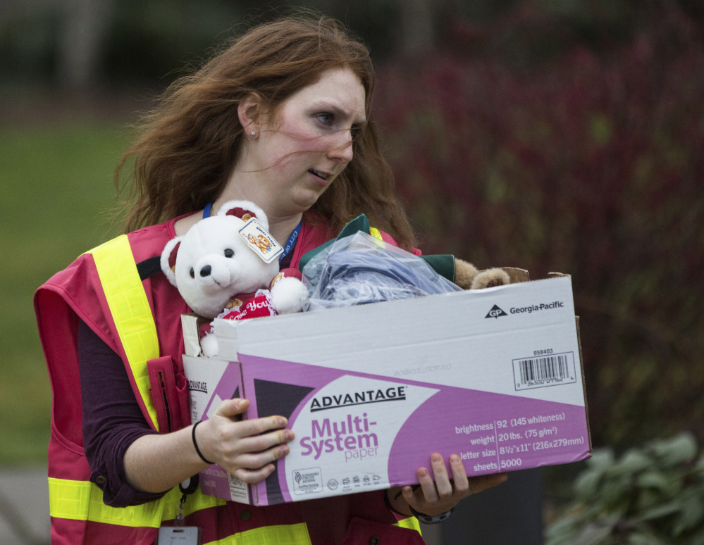 A volunteer carries out a box of supplies, including a teddy bear, from the DuPont, Wash., City Hall following a passenger train derailment in the area earlier Monday.