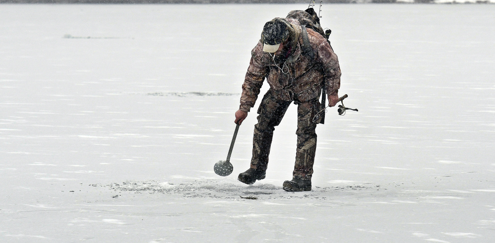 Eric Crowly of Monmouth strains ice in a hole Monday on Cochnewagon Lake in Monmouth. The angler caught one brook trout beneath 5 inches of ice along the shoreline.