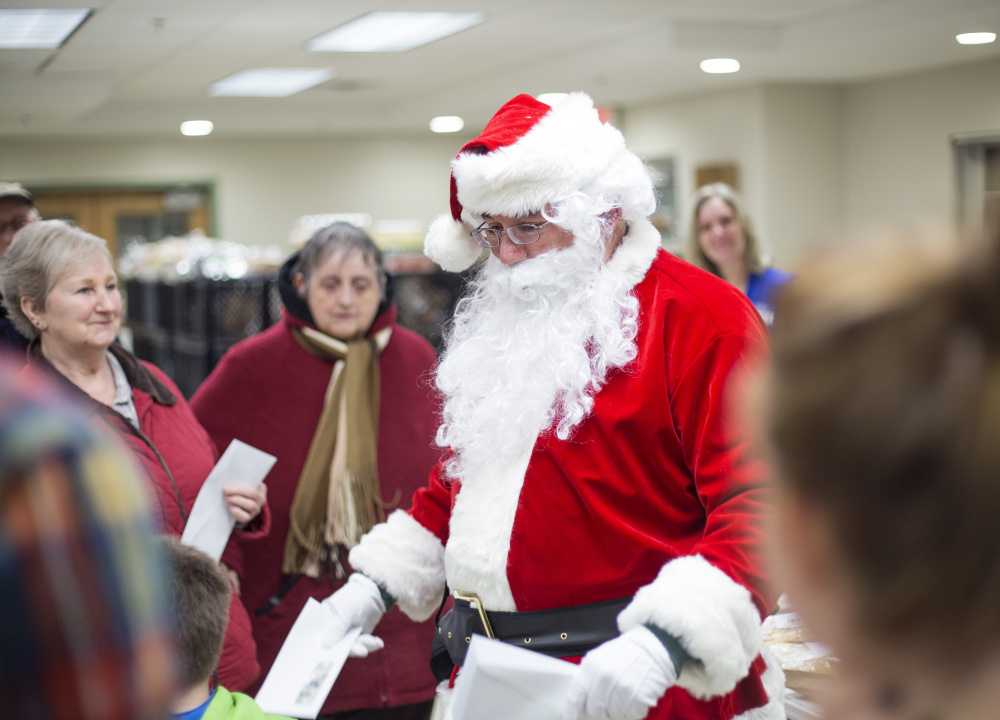 A Secret Santa passes out $100 bills at the Standish Food Pantry on Wednesday.