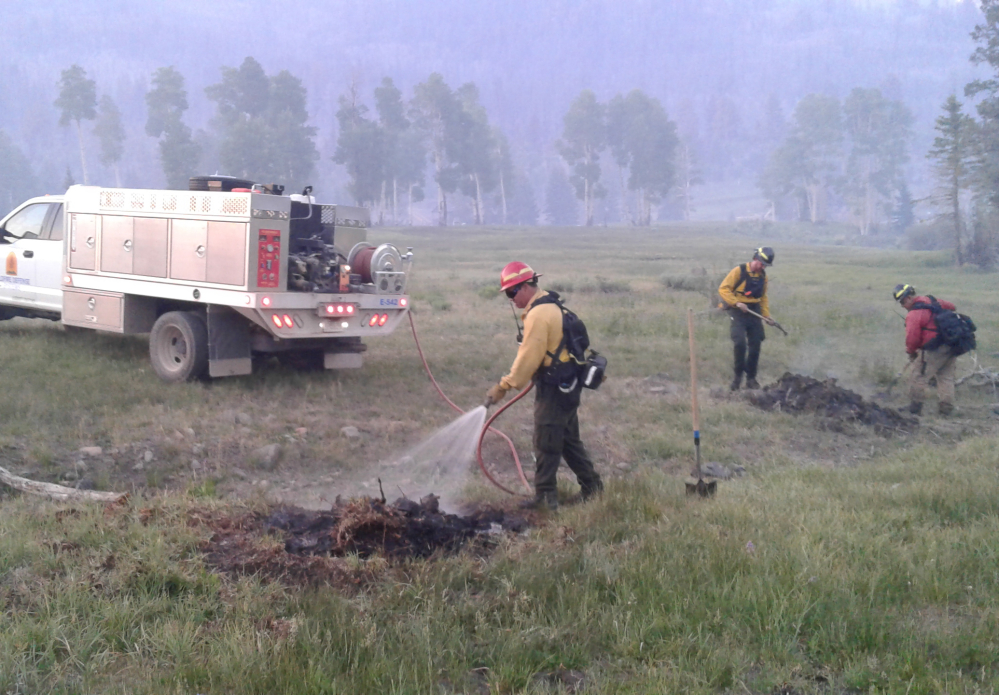 This photo from last July provided by Chubb shows Wildfire Defense Systems, Inc. firefighters mopping up spot fires on a client's property during a wildfire in Panguitch, Utah.