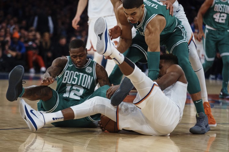 New York's Frank Ntilikina, bottom center, competes for the ball with Boston's Terry Rozier, left, and Jayson Tatum in the first half Thursday night in New York.