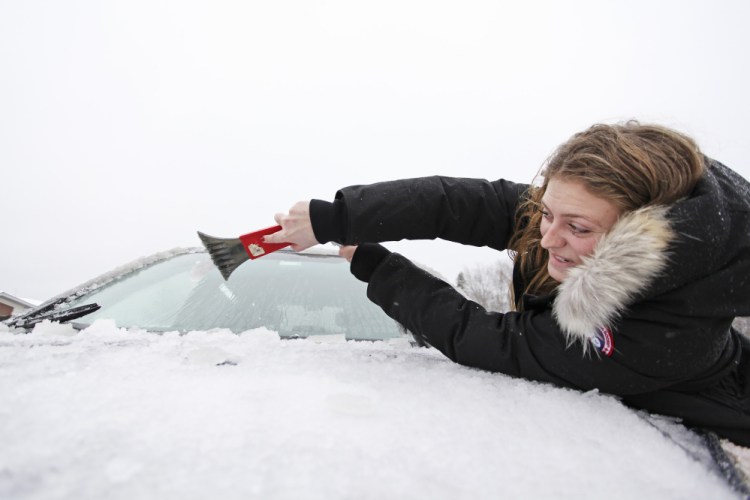 Madeline Paquette of Newton, Mass., reaches to clear ice from her windshield at the northbound Kennebunk rest area of the Maine Turnpike on Saturday morning.
