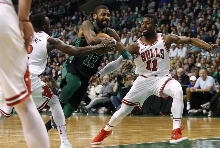 Kyrie Irving of the Celtics drives between Chicago's David Nwaba, right, and Jerian Grant during Saturday's game in Boston. Irving scored 25 points in a 117-92 victory.