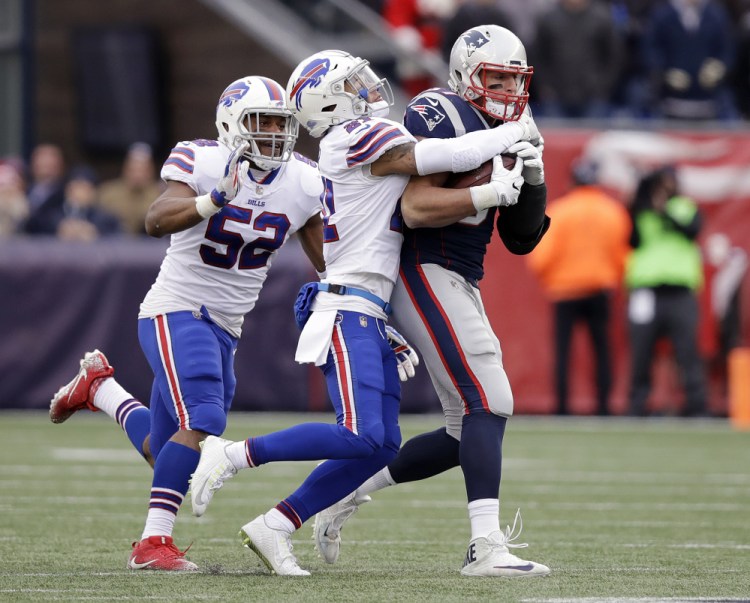 Buffalo Bills safety Jordan Poyer, center, tackles New England Patriots tight end Rob Gronkowski, right, after he caught a pass during the second half Sunday in Foxborough, Mass.