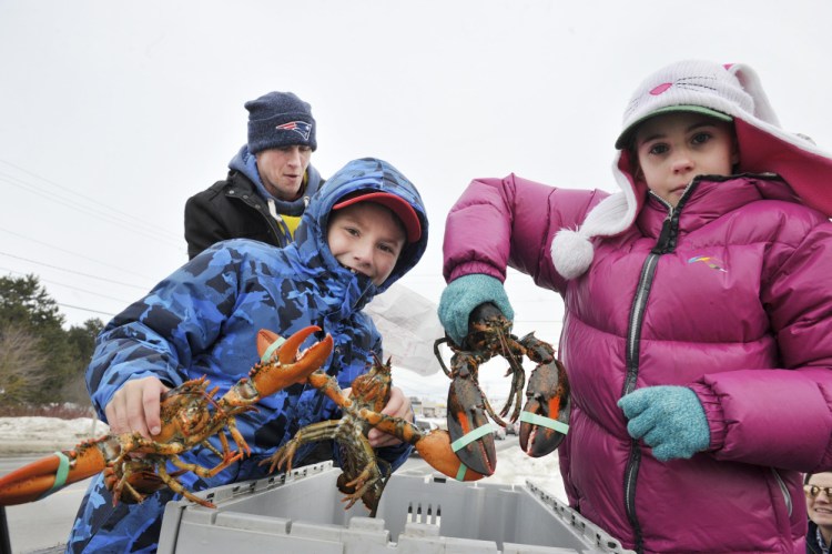 Lobsterman Noah Ames, his daughter Nadia, 10, right, and Aiden Willis, 9, give away lobsters to anyone in need Sunday in Thomaston. This year, Ames distributed over 400 pounds of lobster.