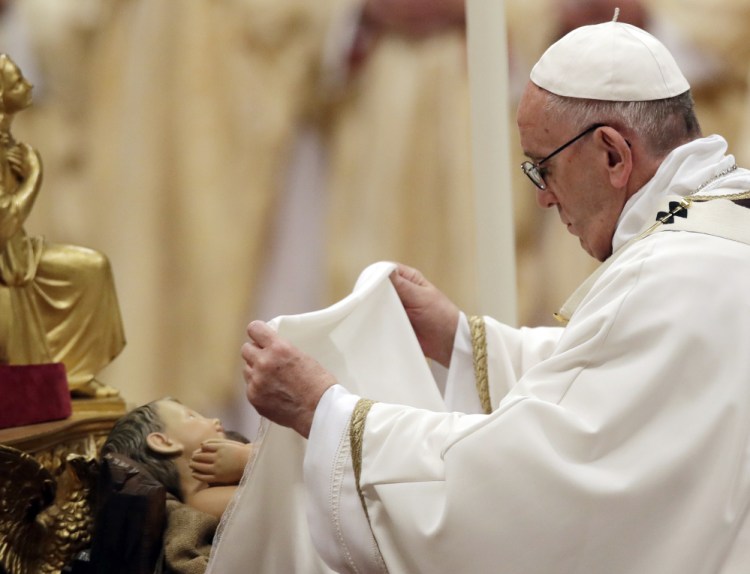 Pope Francis unveils a statue of the baby Jesus as he celebrates the Christmas Eve vigil Mass in St. Peter's Basilica at the Vatican on Sunday.