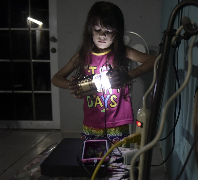Melanie Oliveras Gonzalez, 6, holds a lantern Thursday in the living room of her house in Morovis, Puerto Rico. The U.S. Army Corps of Engineers has said it likely won't be until May that all of the island territory is electrified.