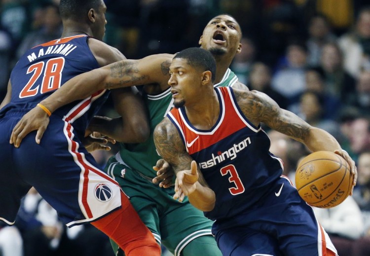 Washington Wizards' Bradley Beal (3) drives past Boston Celtics' Marcus Smart, behind, during the first quarter of an NBA basketball game in Boston, Monday, Dec. 25, 2017. (AP Photo/Michael Dwyer)