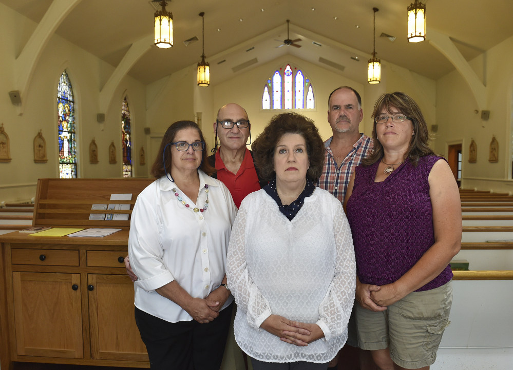 Seen in an Aug. 22, 2017 photo, a group of five Roman Catholics in Glastonbury are appealing Archbishiop Leonard P. Blair's plan to merge their two parishes, St. Augustine and St. Paul. Pictured in the sanctuary at St. Augustine, from the left,  are Joyce Giannelli, Gary Giannelli, Suzanne Allen, Martin Ethier and Dee Ethier. (Cloe Poisson/Hartford Courant via AP)