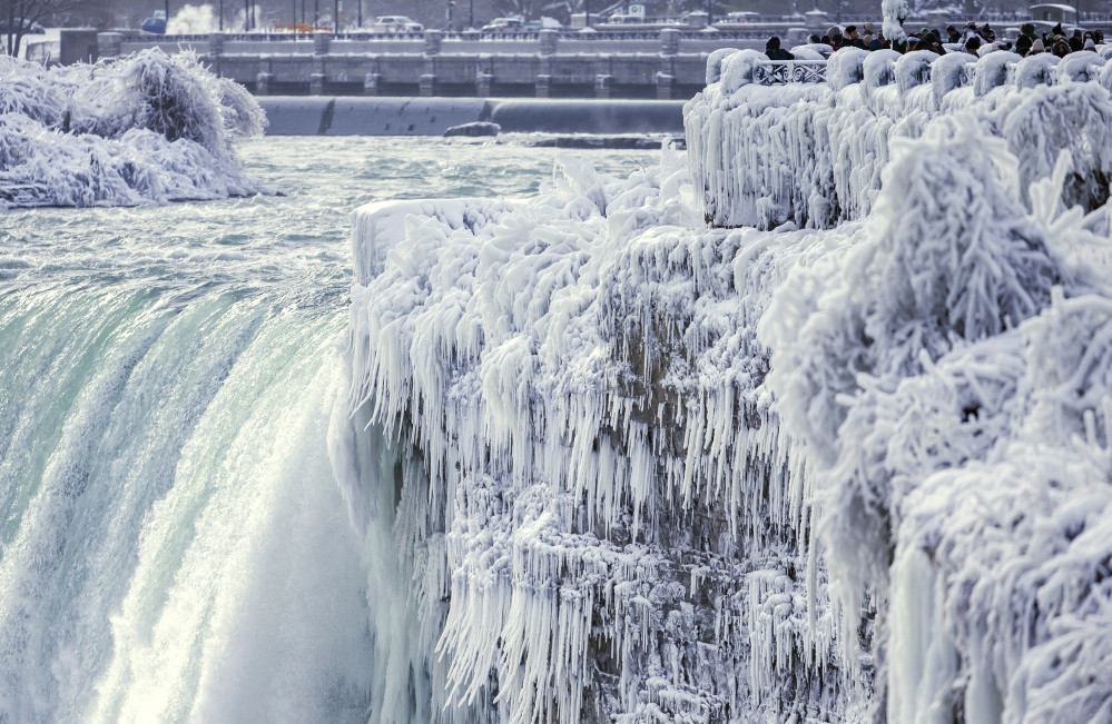 Visitors take photographs at the brink of the Horseshoe Falls in Niagara Falls, Ontario, as cold weather continued through much of the province Friday.