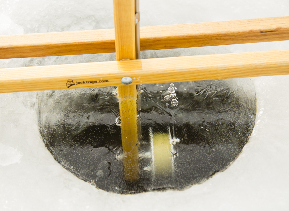 With the temperature at 10 below zero, ice fishing holes quickly freeze over on Barkers Pond in Lyman on Saturday.