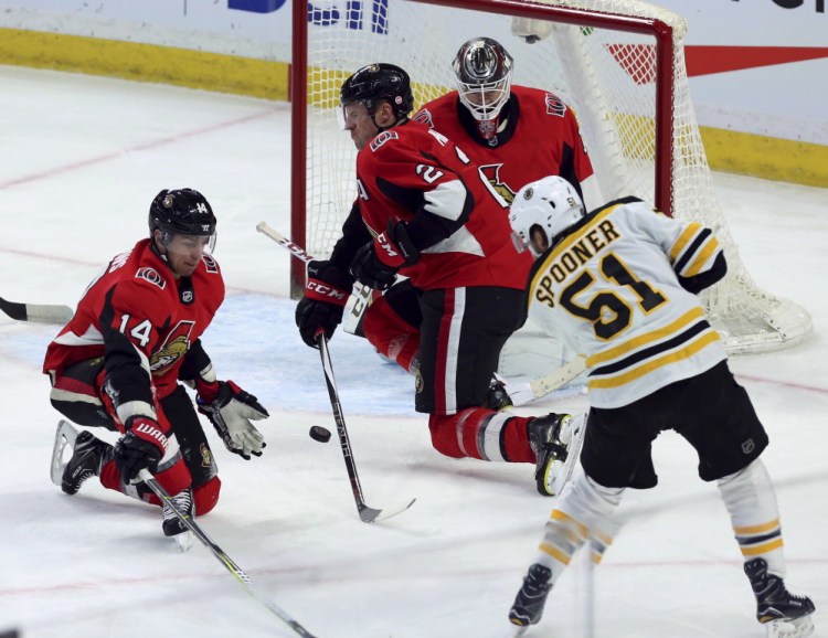 Boston Bruins' Ryan Spooner shoots the puck and scores as Senators' Alexandre Burrows (14) and Dion Phaneuf (2) defend during the first period Saturday in Ottawa, Ontario.