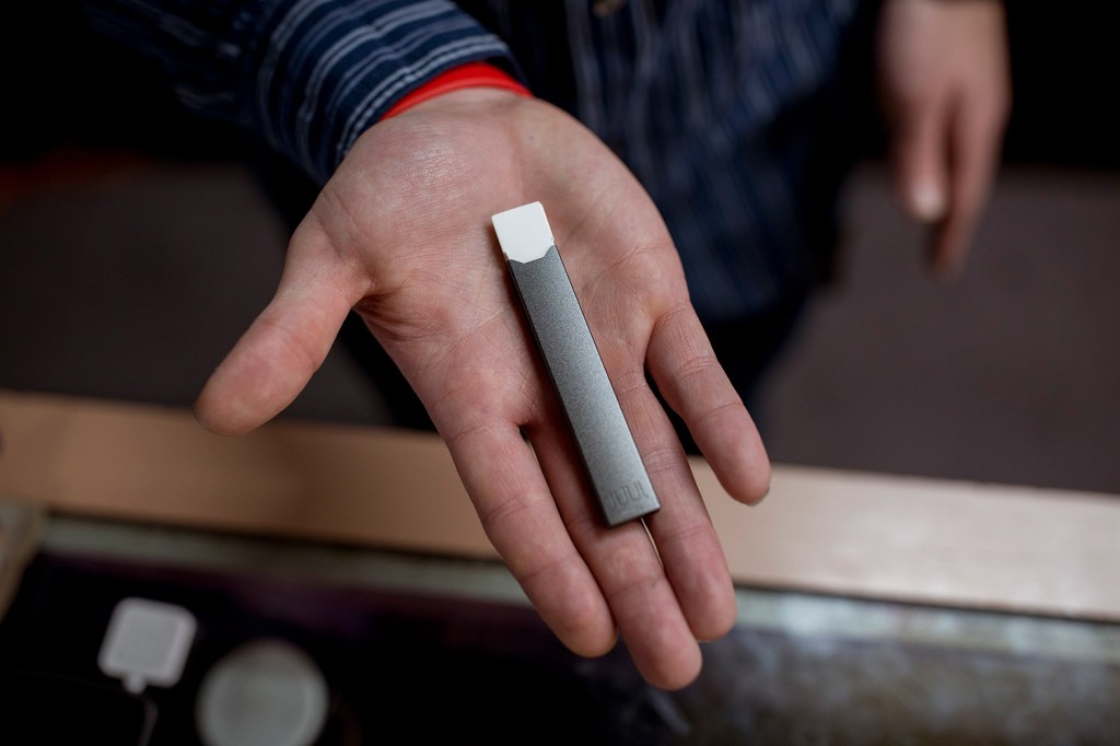 Ryan Purington, an employee at Lucky Juju in Portland, holds a JUUL vaporizer. The easily hidden devices are seen as harmless by some teenagers.